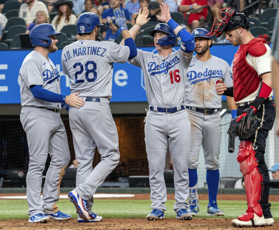 Los Angeles Dodgers designated hitter J.D. Martinez (28) is congratulated at home plate by teammates Max Muncy, left, Will Smith (16) and David Peralta, second from right, after his three-run home run that also scored Smith and Muncy as Texas Rangers catcher Mitch Garver, right, looks on during the fourth inning of a baseball game Saturday, July 22, 2023, in Arlington, Texas. (AP Photo/Jeffrey McWhorter)