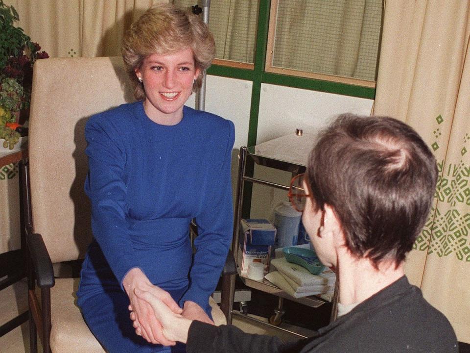 Princess Diana wearing blue suit shakes hands with AIDS patient