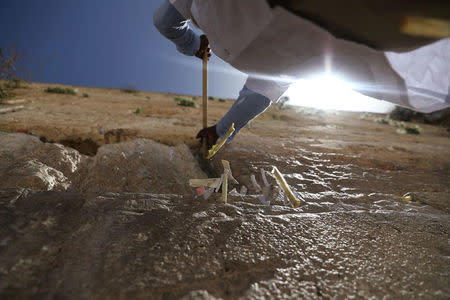 A man uses a stick to clear notes placed in the cracks of the Western Wall, Judaism's holiest prayer site, to create space for new notes ahead of the Jewish holiday of Passover, in Jerusalem's Old City, March 20, 2018. REUTERS/Ammar Awad