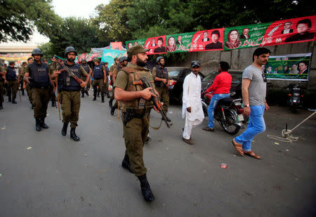 Soldiers patrol around tents set up by different political parties to help voters outside a polling station in Lahore, Pakistan September 17, 2017. REUTERS/Mohsin Raza