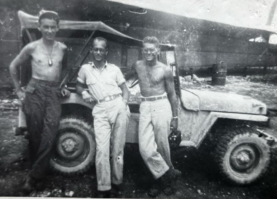 Three men lean against a jeep in a military-approved photo from New Caledonia in the South Pacific.