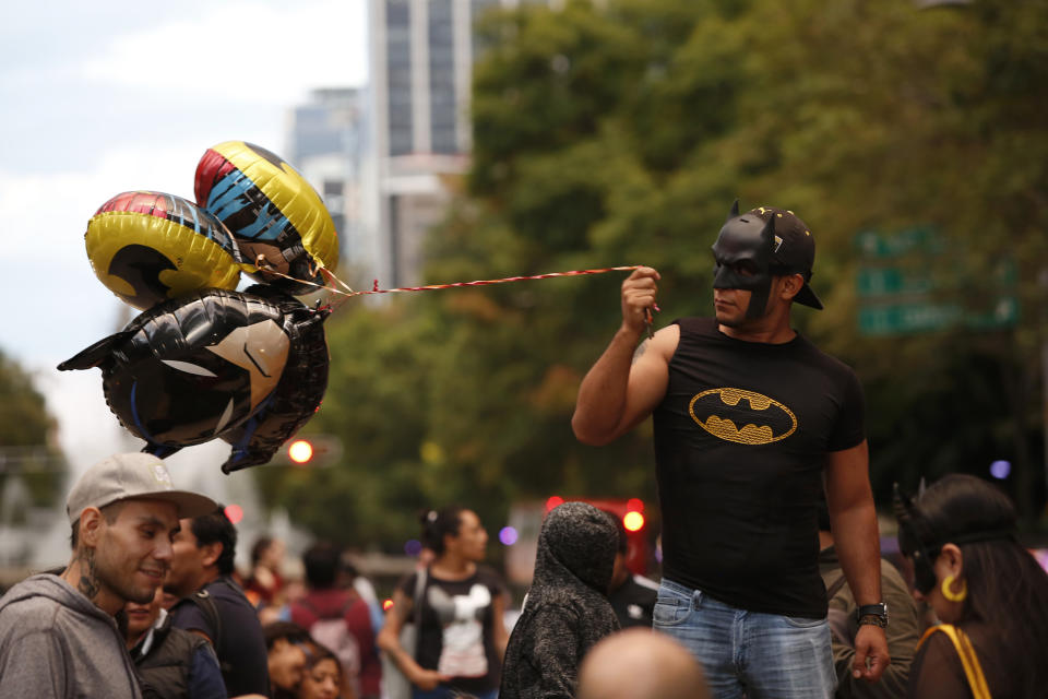 A man holds Batman balloons before the Bat signal lighting during the commemorating of Batman's 80th anniversary in Mexico City, Saturday, Sept. 21, 2019. (AP Photo/Ginnette Riquelme)