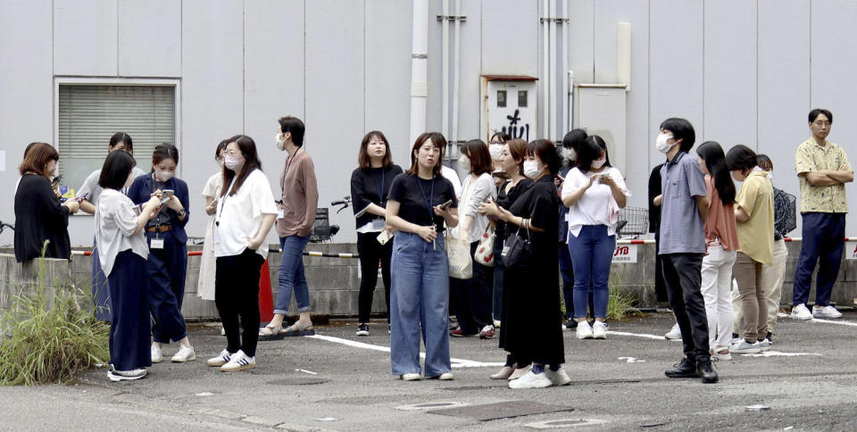 People stand outside a building after an earthquake (Kyodo News via AP)