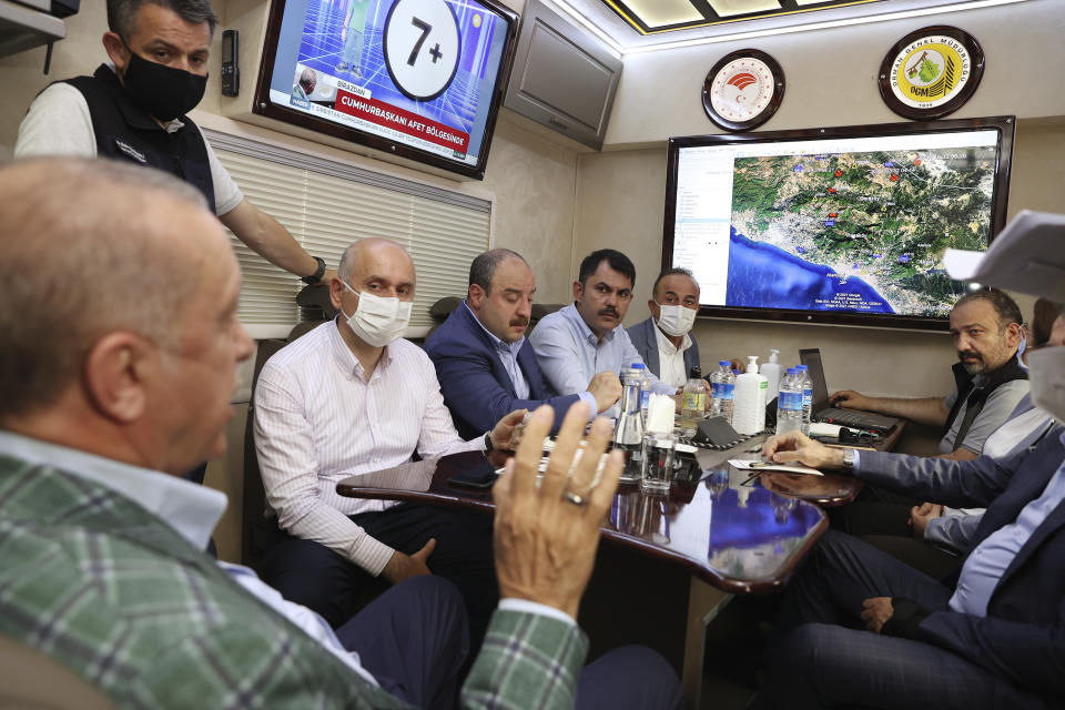 Turkey's President Recep Tayyip Erdogan, front, speaks to his ministers about the wildfires in Manavgat, Antalya, Turkey, Saturday, July 31, 2021. The death toll from wildfires raging in Turkey's Mediterranean towns rose to six Saturday after two forest workers were killed, the country's health minister said. Fires across Turkey since Wednesday burned down forests, encroaching on villages and tourist destinations and forcing people to evacuate.(Turkish Presidency via AP, Pool)