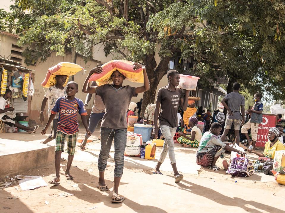 Young boys displaced by violence in northern Mozambique carry sacks of food on their head after purchasing them with vouchers (John Wessels/AFP via Getty Images)