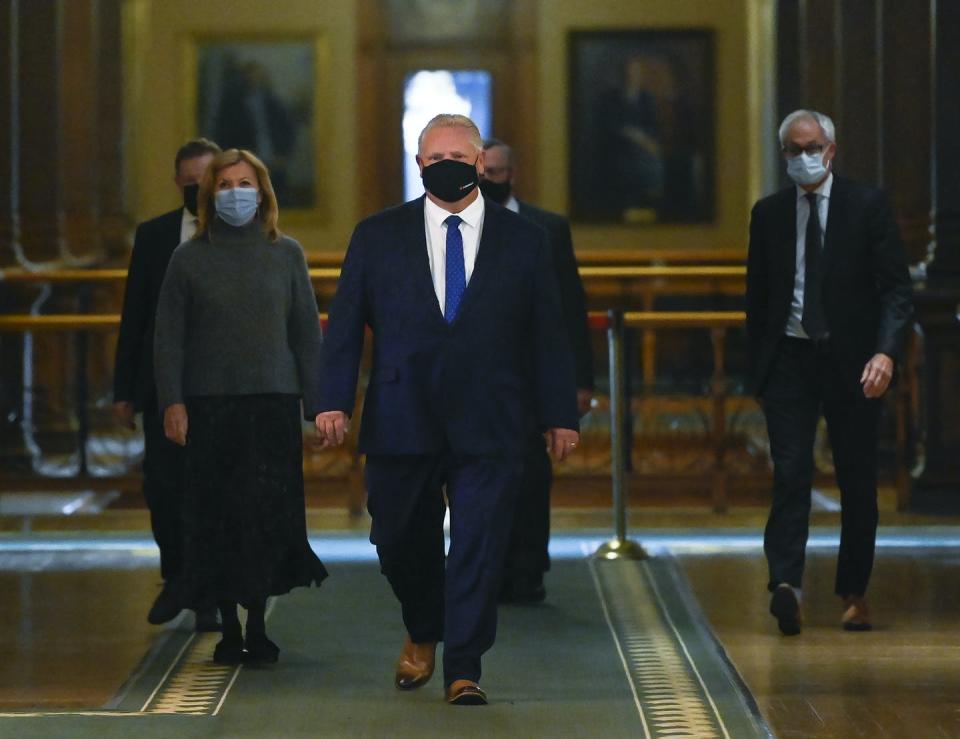 Doug Ford, wearing a mask, walks into a news conference at Queen's Park.