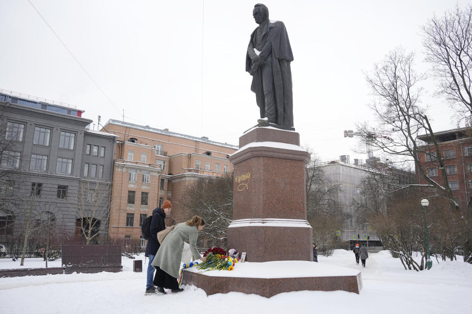 People lay flowers to the monument of Ukrainian author Taras Shevchenko to mark one year since the start of the Russian campaign in Ukraine in St. Petersburg, Russia, Friday, Feb. 24, 2023. OVD-Info, a group that tracks political arrests, said that several people were detained in St. Petersburg after bringing flowers to the Shevchenko monument. (AP Photo/Dmitri Lovetsky)