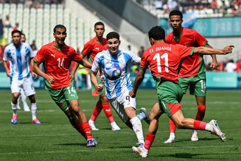 El delantero argentino Julián Álvarez disputa el balón con el defensor marroquí Zakaria El Ouahdi durante el partido inaugural del torneo masculino de fútbol del Grupo B de los Juegos Olímpicos de París, en el estadio Geoffroy-Guichard en Saint-Étienne el 24 de julio de 2024. (Arnaud FINISTRE)