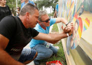 <p>Saul Barrios (L) leaves his handprint on a mural that contains an image of his deceased son Alejandro Barrios Martinez, with the help of artist Yuri Karabash, at the memorial outside the Pulse Nightclub on the one-year anniversary of the shooting in Orlando, Florida, June 12, 2017. (Scott Audette/Reuters) </p>