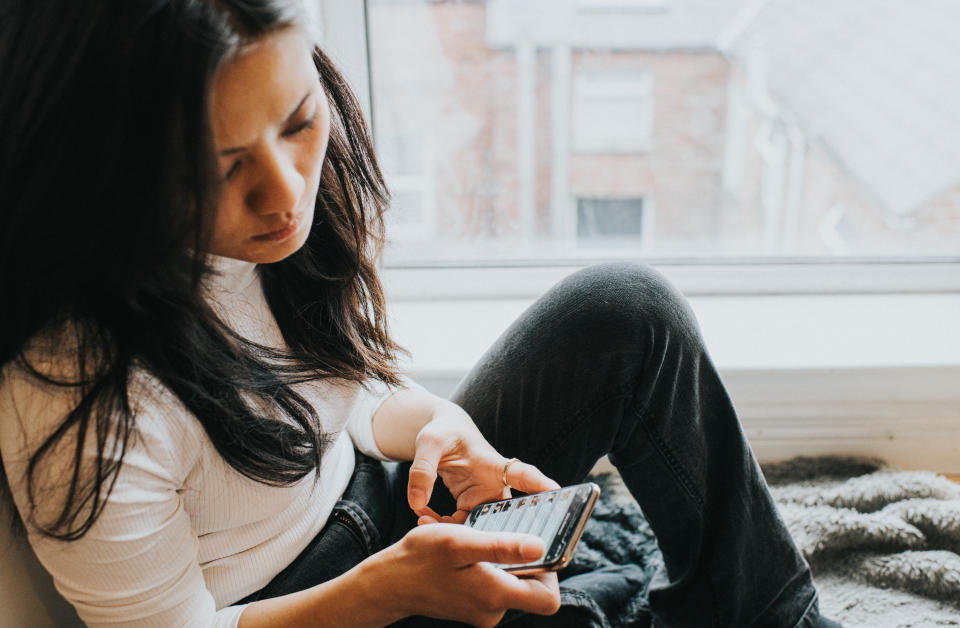 An elevated view of a concerned looking woman looking down at her mobile phone device. Space for copy.