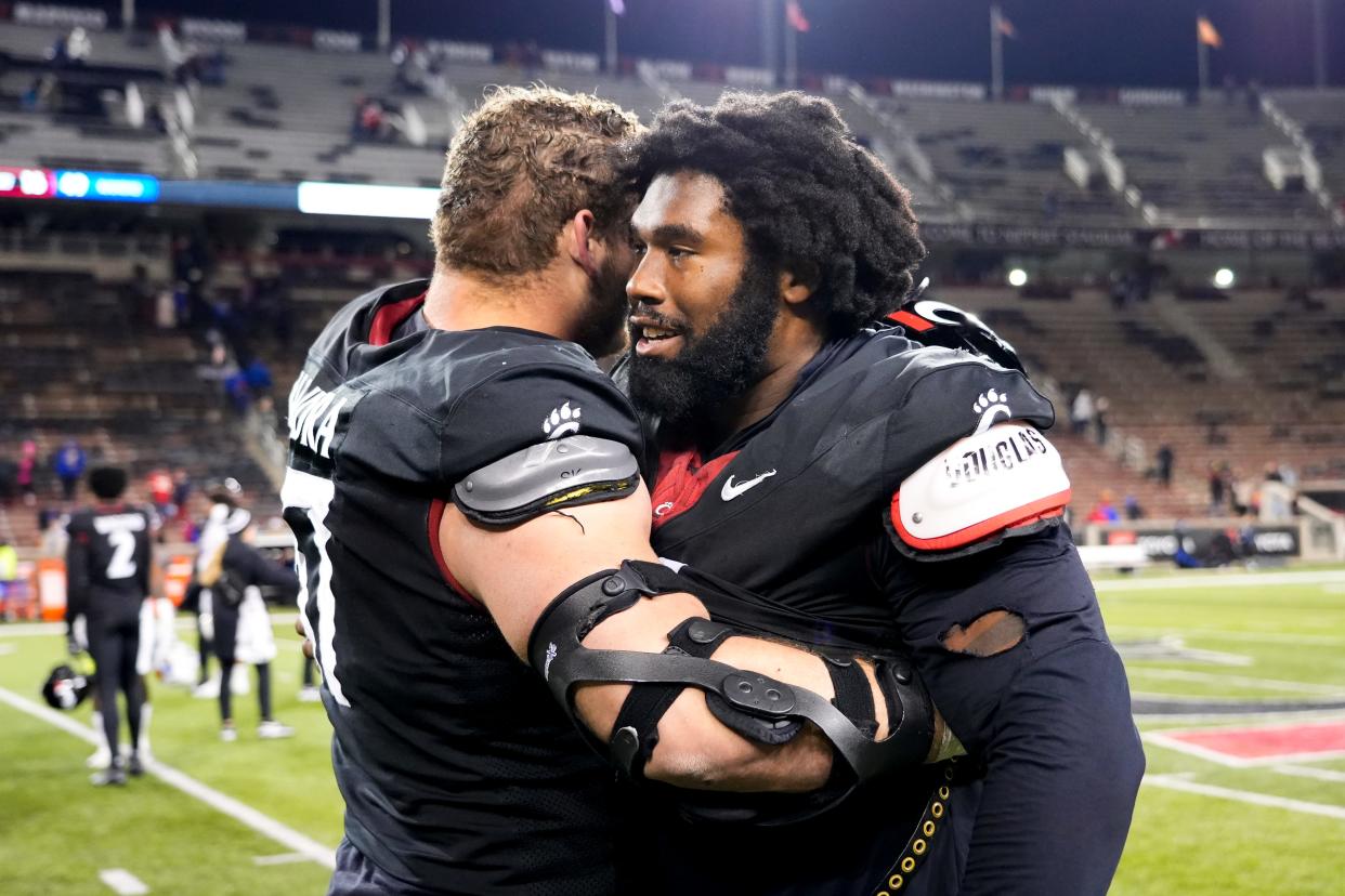 Cincinnati Bearcats offensive lineman Luke Kandra (67), left, and Cincinnati Bearcats defensive end Jowon Briggs (0) embrace after losing the NCAA college football game between the Cincinnati Bearcats and Kansas Jayhawks on Saturday, Nov. 25, 2023, at Nippert Stadium in Cincinnati. Kansas won 49-16.