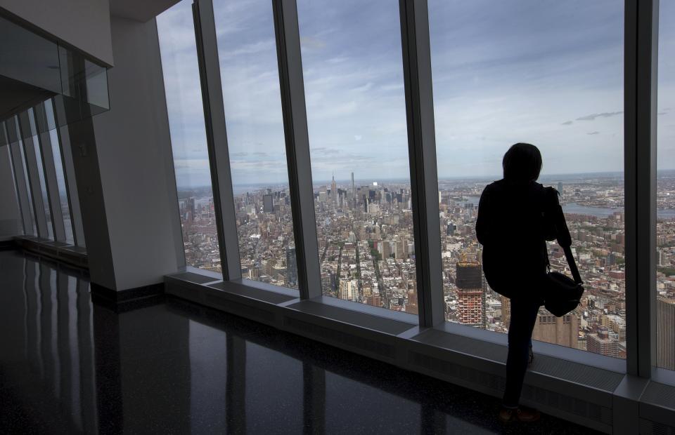 Media member looks out the window at the Manhattan skyline from the One World Observatory observation deck on the 100th floor of the One World Trade center tower in New York