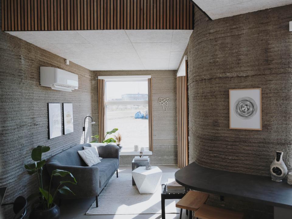 Inside 3DCP Group's 3D printed tiny home with a living room, windows, and a desk.
