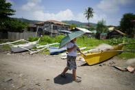 A boy walks past small boats at a coastal village in Batangas province, Philippines on Wednesday Aug. 9, 2023. The Philippines is seeing one of the world's biggest buildouts of natural gas infrastructure. This could impact nearby coral reefs and fishing communities. (AP Photo/Aaron Favila)