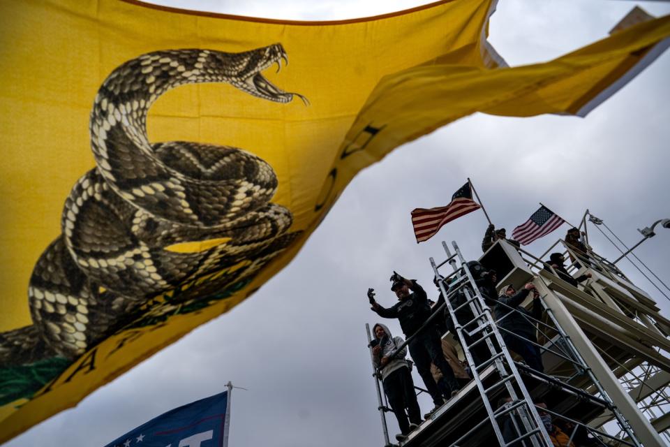 People gesture and wave flags atop scaffolding