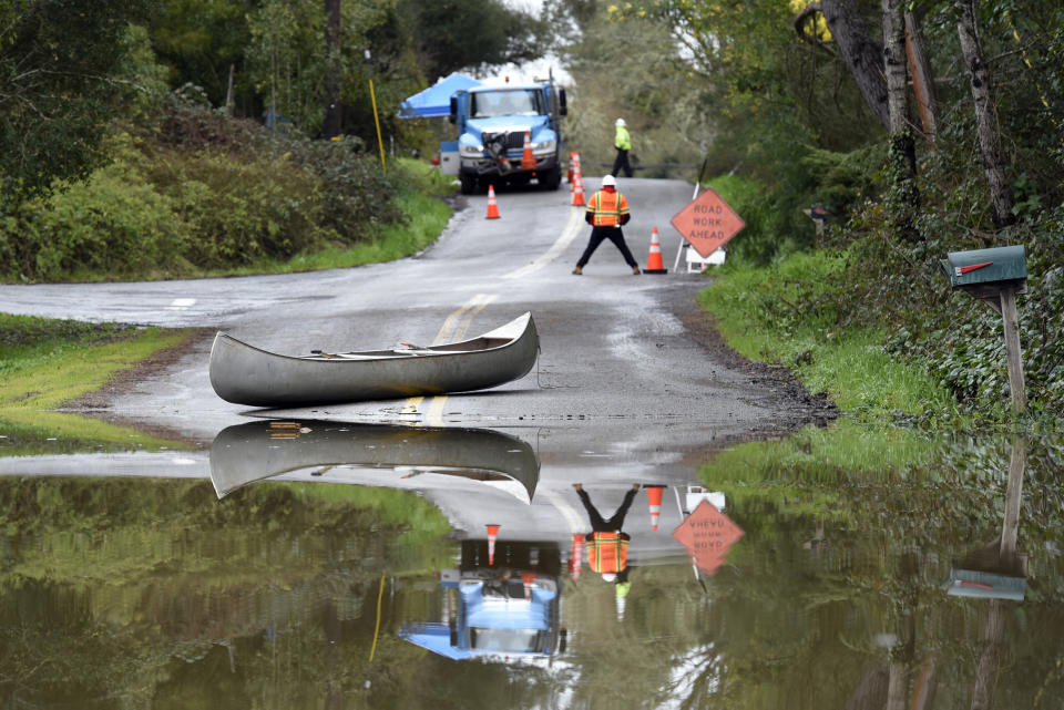 Pacific Gas & Electric workers and a canoe are seen on a street flooded by the Russian River in Forestville, Calif., on Feb. 27, 2019. (Photo: Michael Short/AP)