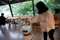 A customer picks up her drink at a cafe where a robot that takes orders, makes coffee and brings the drinks straight to customers is being used in Daejeon