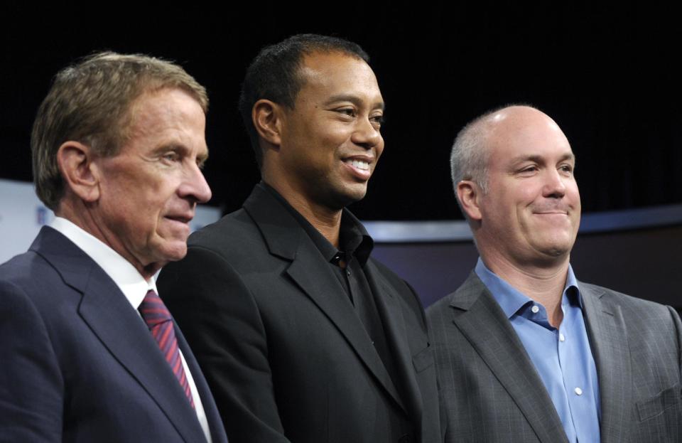 Tiger Woods, flanked by PGA Tour commissioner Tim Finchem, left and Quicken Loans Chief Executive Officer Bill Emerson, right, pose for a photo at the Newseum in Washington, Monday, March 24, 2014, after announcing that Quicken Loans had signed a multi-year agreement to become the title sponsor of the Quicken Loans National to be played at Congressional Country Club in Bethesda, Md., in June. (AP Photo/Susan Walsh)