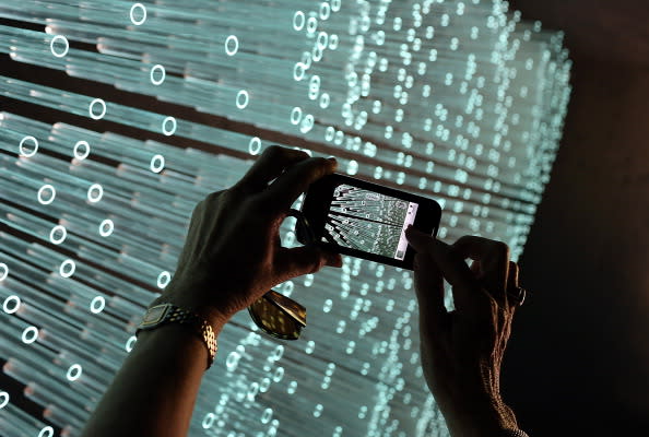 A U.C. Berkeley Botanical Gardens visitor uses a cellular phone to photograph the art installation 'SOL Grotto' that was made by using glass tubes that were to be used by the now defunct solar company Solyndra on August 23, 2012 in Berkeley, California. Berkeley artists Ronald Rael and Virginia San Fratello have created the art installation 'SOL Grotto' by using an estimated 1,400 of the 24 million unused specialized glass tubes to be used in tubular solar panels made by now bankrupt solar power firm Solyndra. The installation is part of a larger exhibit at the UC Berkeley Botanical Garden called 'Natural Discourse' that runs through January 2013. (Photo by Justin Sullivan/Getty Images)