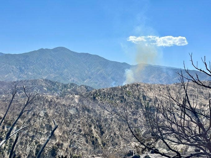 A plume of smoke rises above terrain charred by the Post Fire on Friday. The brush fire that burned through 15,690 acres in Los Angeles and Ventura counties was 61% contained, authorities said.