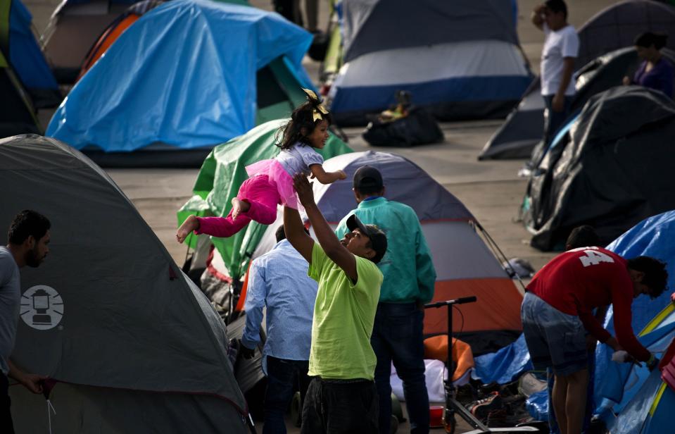 A migrant plays with a girl at the new shelter where he and others were transferred after the sanitary conditions worsened at a previous shelter in Tijuana, Mexico, Sunday, Dec. 2, 2018. Aid workers and humanitarian organizations expressed concerns about the unsanitary conditions at the sports complex where more than 6,000 Central American migrants were packed into a space adequate for half that many people and where lice infestations and respiratory infections are rampant. (AP Photo/Ramon Espinosa)