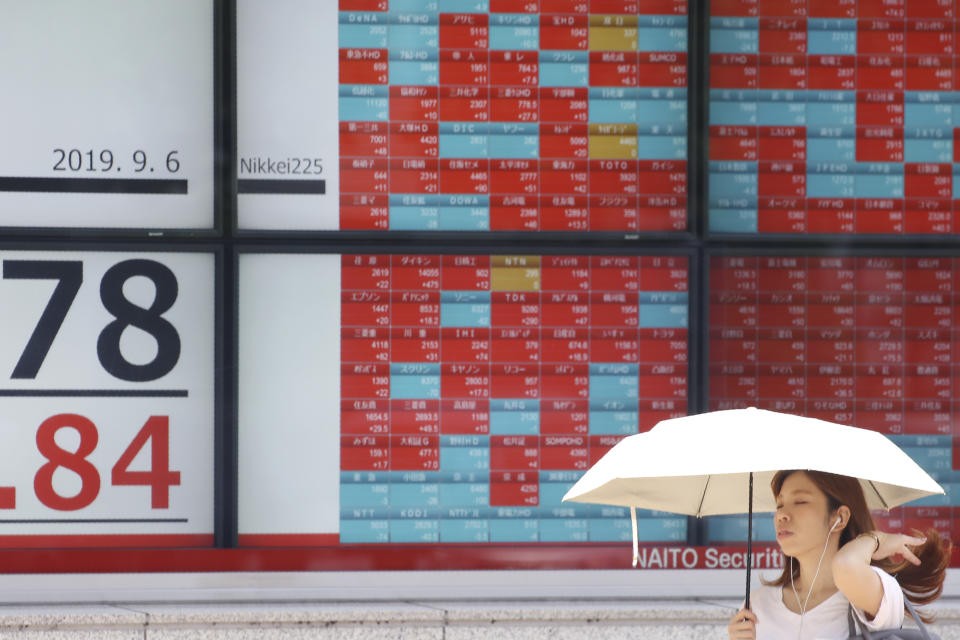 A woman walks by an electronic stock board of a securities firm in Tokyo, Friday, Sept. 6, 2019. Asian shares rose Friday as investors cheered plans for more trade negotiations between Washington and Beijing and drew encouragement from positive data about the U.S. economy. (AP Photo/Koji Sasahara)