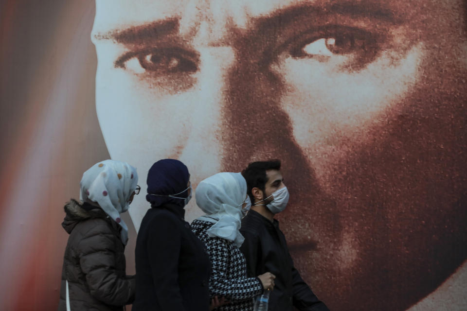 FILE - In this Tuesday, Nov. 17, 2020, file photo, people wearing masks to help protect from the spread of the coronavirus walk past a picture of Mustafa Kemala Ataturk, modern Turkey's founder in Istanbul. When Turkey changed the way it reports daily COVID-19 infections, it confirmed what medical groups and opposition parties have long suspected — that the country is faced with an alarming surge of cases that is fast exhausting the Turkish health system. The official daily COVID-19 deaths have also steadily risen to record numbers in a reversal of fortune for the country that had been praised for managing to keep fatalities low. With the new data, the country jumped from being one of the least-affected countries in Europe to one of the worst-hit.(AP Photo/Emrah Gurel, File)