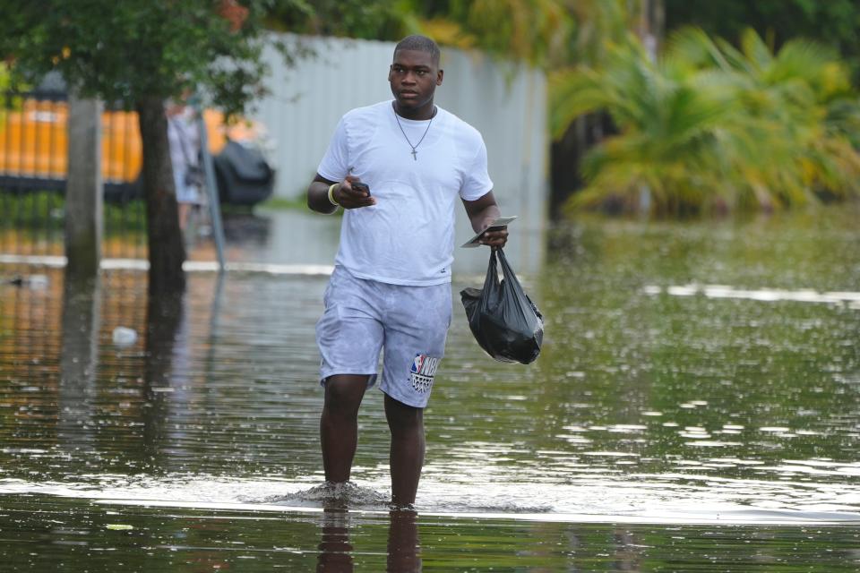 A man walks on a flooded street on his way to work, Thursday, June 13, 2024, in North Miami, Fla. A tropical disturbance has brought a rare flash flood emergency to much of southern Florida. Floridians prepared to weather more heavy rainfall on Thursday and Friday. (AP Photo/Marta Lavandier)