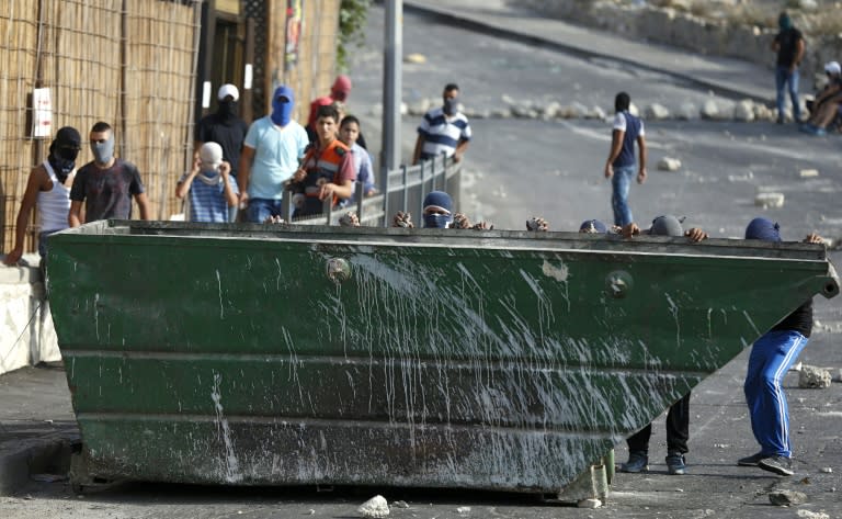 Palestinian youths take shelter behind a garbage container during clashes with Israeli police in the east Jerusalem Arab neighbourhood of Issawiya following unrest at the Al-aqsa mosque compounds on September 13, 2015