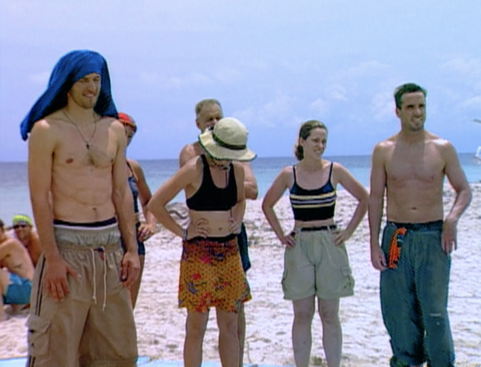 Contestants stand in a chaotic formation blocking each other on the beach on Survivor: Borneo