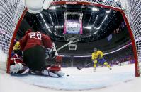 Sweden's Daniel Alfredsson (R) comes in to score a goal on a puck not held onto by Switzerland's goalie Reto Berra (20) during the third period of their men's ice hockey game at the 2014 Sochi Winter Olympics, February 14, 2014. REUTERS/Martin Rose/Pool (RUSSIA - Tags: OLYMPICS SPORT ICE HOCKEY)