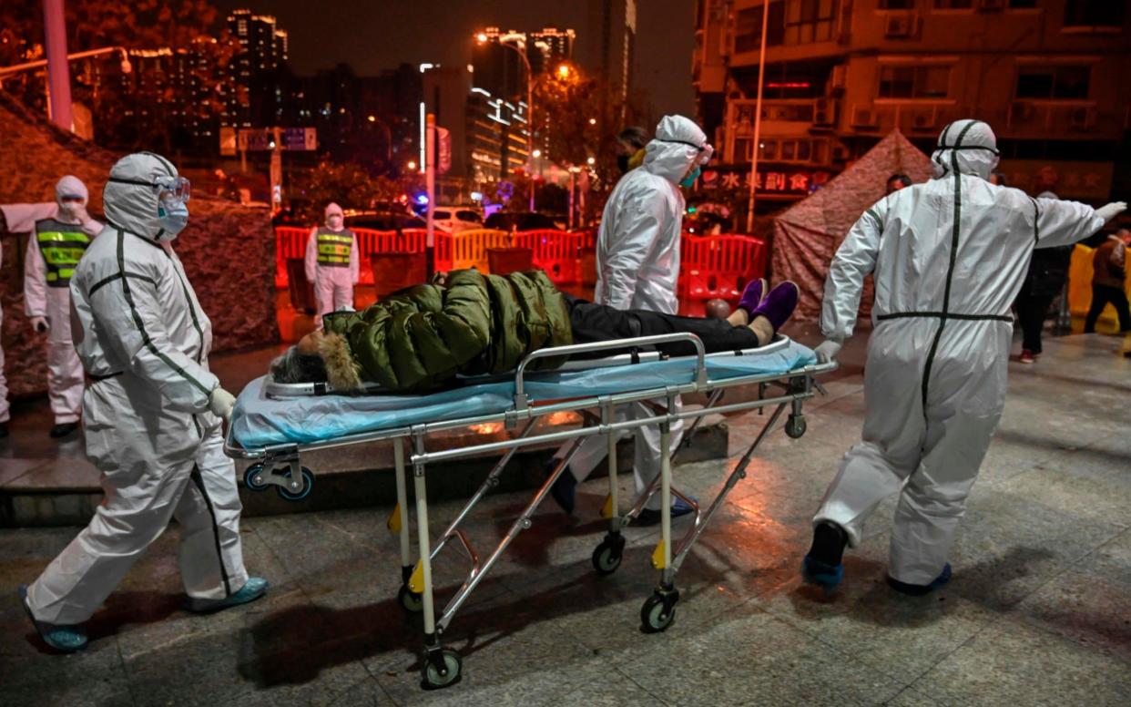 Medical staff members wearing protective clothing to help stop the spread of a deadly virus which began in the city, arrive with a patient at the Wuhan Red Cross Hospital in Wuhan on January 25, 2020 - HECTOR RETAMAL/AFP via Getty Images