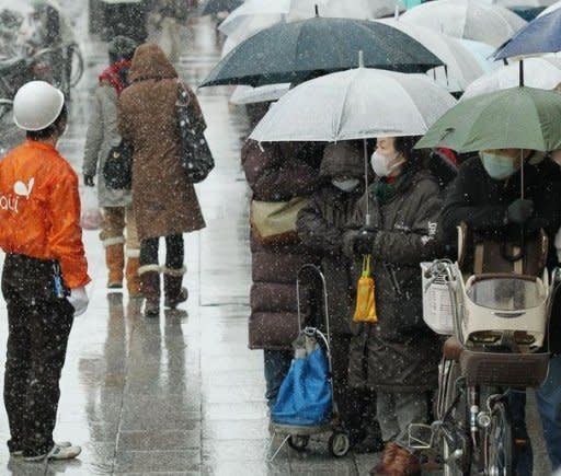 People queue up in the snow to buy food and daily necessities outside a supermarket in Sendai in Miyagi prefecture on March 16, 2011