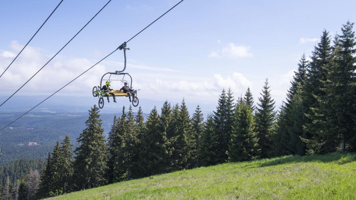 low angle view of mountain bikers sitting on chair lift