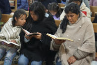 Peru's future first lady Lilia Paredes, right, reads from the Bible while sitting next to her younger sister Yenifer, and her 9-year-old daughter Alondra, during a church service in which neighbors were invited to say goodbye before the family's departure to Lima, at the Nazarene church in Chugur, Peru, Thursday, July 22, 2021. Her husband, leftist Pedro Castillo catapulted from unknown to president-elect with the support of the country's poor and rural citizens, many of whom identify with the struggles the teacher has faced. (AP Photo/Franklin Briceno)