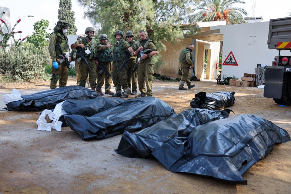 Los soldados israelíes se preparan para retirar los cuerpos de sus compatriotas, muertos durante un ataque de militantes palestinos, en Kfar Aza, al sur de Israel, en la frontera con la Franja de Gaza, el 10 de octubre de 2023. (Foto de JACK GUEZ/AFP vía Getty Images)