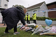 A woman places a floral tribute on the road leading to the Belfairs Methodist Church in Eastwood Road North, in Leigh-on-Sea, Essex, England, Saturday, Oct. 16, 2021. David Amess, a long-serving member of Parliament was stabbed to death during a meeting with constituents at a church in Leigh-on-Sea on Friday, in what police said was a terrorist incident. A 25-year-old man was arrested in connection with the attack, which united Britain's fractious politicians in shock and sorrow. (AP Photo/Alberto Pezzali)