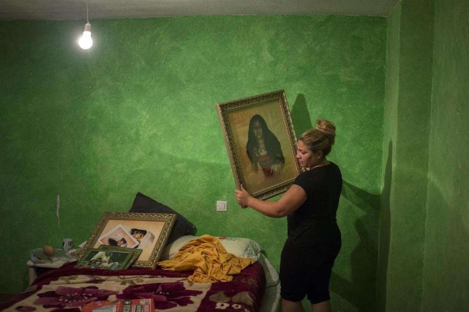 Fernando Montoya Jimenez's 32-year old daughter removes pictures from his room during his eviction in Madrid, Spain, Wednesday, July 23, 2014. Fernando Montoya Jimenez, 61, lived with his son Jesus Miguel, 14, and his 16-year old daughter Diana, who is six months pregnant, in an apartment owned by the Madrid Community state housing company for more than 20 years, paying subsidized rent. Jimenez who has a disability and epilepsy and has spent time in prison for prior convictions, lives from a state benefit of euro 311 (US$419) per month. The state housing company evicted him and his family after freezing his account with them when he failed to pay his rent. (AP Photo/Andres Kudacki)