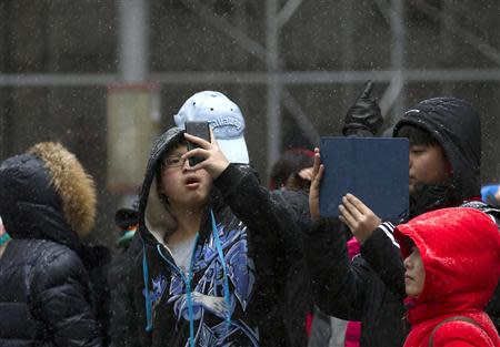 School children take photos during a snow storm in Manhattan's financial district in New York January 21, 2014. REUTERS/Brendan McDermid