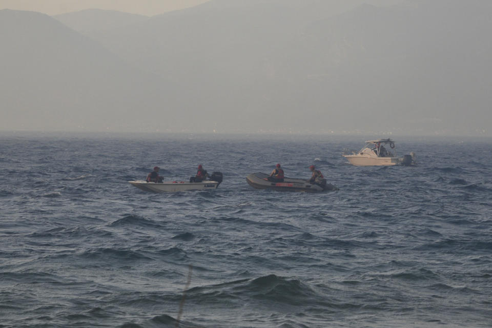 Firefighters and volunteers in vessels stand by the beach during a wildfire near Lampiri village, west of Patras, Greece, Saturday, Jul. 31, 2021. The fire, which started high up on a mountain slope, has moved dangerously close to seaside towns and the Fire Service has send a boat to help in a possible evacuation of people. (AP Photo/Andreas Alexopoulos)