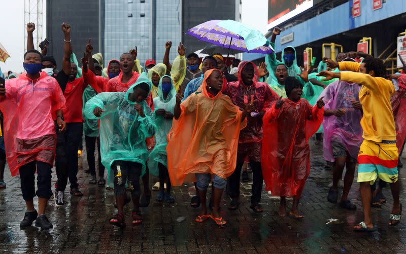 Demonstrators wearing raincoats shout slogans during a protest over alleged police brutality, in Lagos