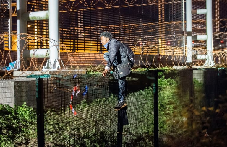 A migrant climbs a security fence of a Eurotunnel terminal in Coquelles near Calais, northern France, on July 30, 2015