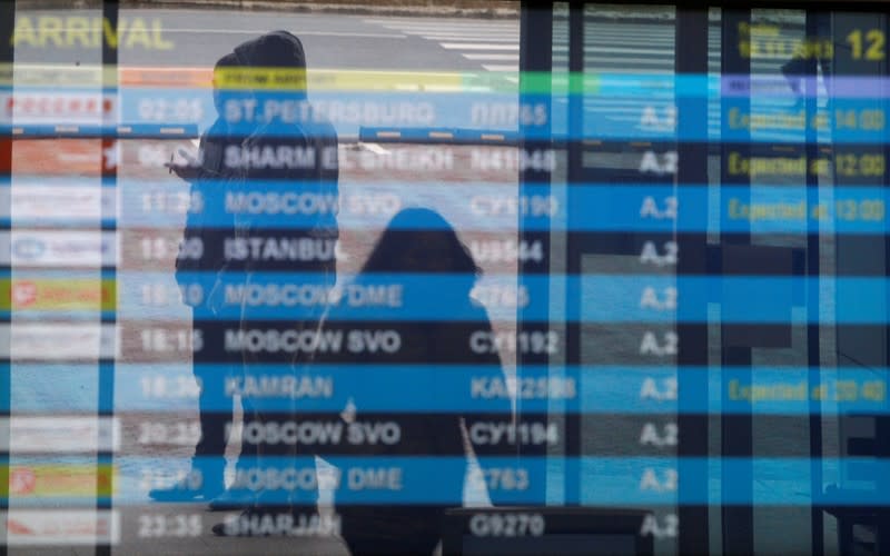 FILE PHOTO: People are seen reflected in a flight information board at Kazan airport, where a Tatarstan Airlines Boeing 737 crashed