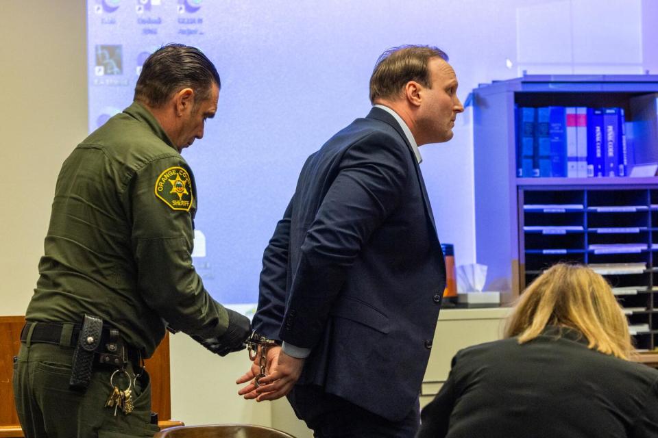 Aaron Romo, right, is escorted out of court by an Orange County sheriff's deputy.