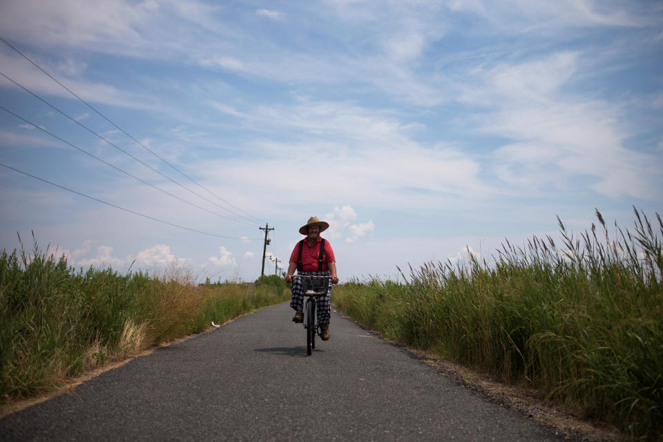 <p>Local resident Wayne Crokett, 72, rides along Factory Road on Tangier Island, Virginia, Aug. 2, 2017. (Photo: Adrees Latif/Reuters) </p>