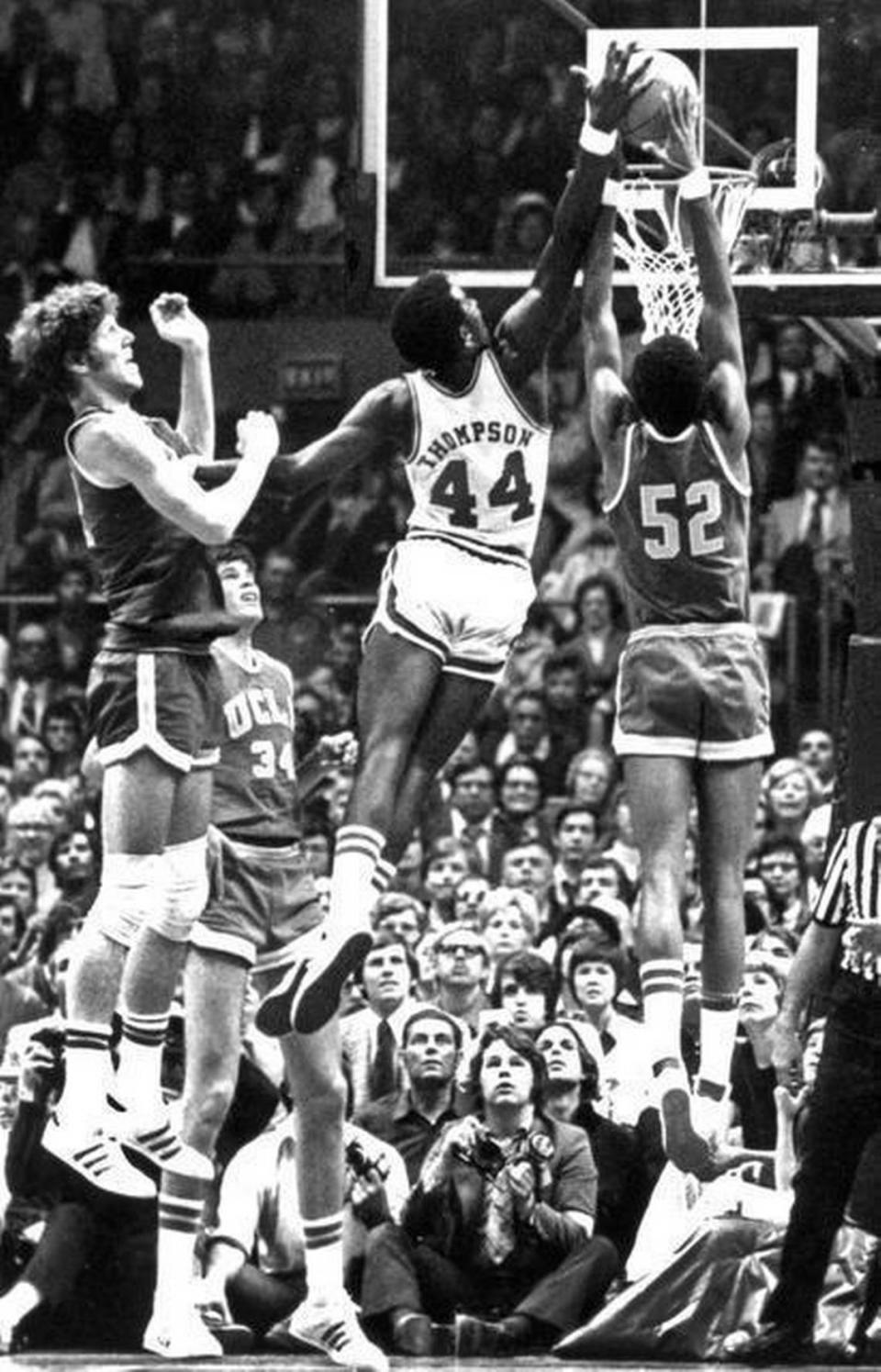 N.C. State’s David Thompson fends off UCLA’s Bill Walton, left, as he soars to block a shot by Keith Wilkes during the national semifinals at the Greensboro Coliseum in 1974. The Wolfpack won 80-77 in double overtime to end the Bruins’ string of seven straight NCAA titles.