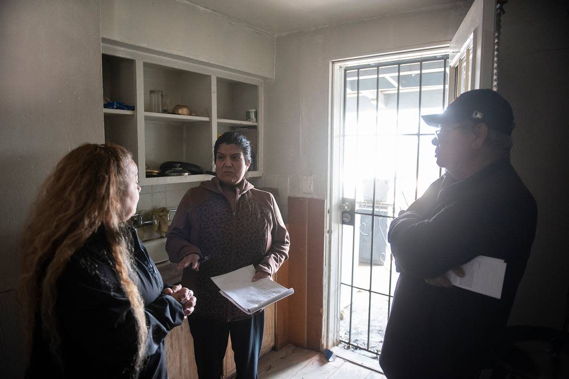 Alicia Rodriguez, president of St. Vincent De Paul Planada Sacred Heart Conference, center, speaks with Gloria Canal, left, and Canal’s father Samuel, right, inside his home that was damaged by floodwater in Planada, Calif., on Thursday, Jan. 12, 2023.