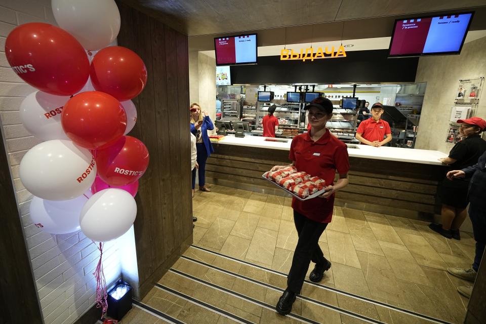 FILE - An employee of the Rostic's restaurant in Tverskaya street carries food while celebrating opening ceremony in Moscow, Russia, Tuesday, April 25, 2023. When Russia invaded Ukraine, companies were quick to respond, some announcing they would get out of Russia immediately, others vowed to curtail sales and new investment. More than a year later, it’s clear: Leaving Russia isn't as easy as the first announcements might have made it seem. (AP Photo/Alexander Zemlianichenko, File)