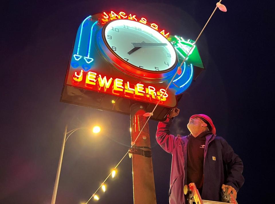 Randy Russell of Salem Sign Co. touches up paint on the Jackson Jewelers clock on Wednesday, Dec. 27, 2023, after it is remounted in front of the business in downtown Salem, Ore.