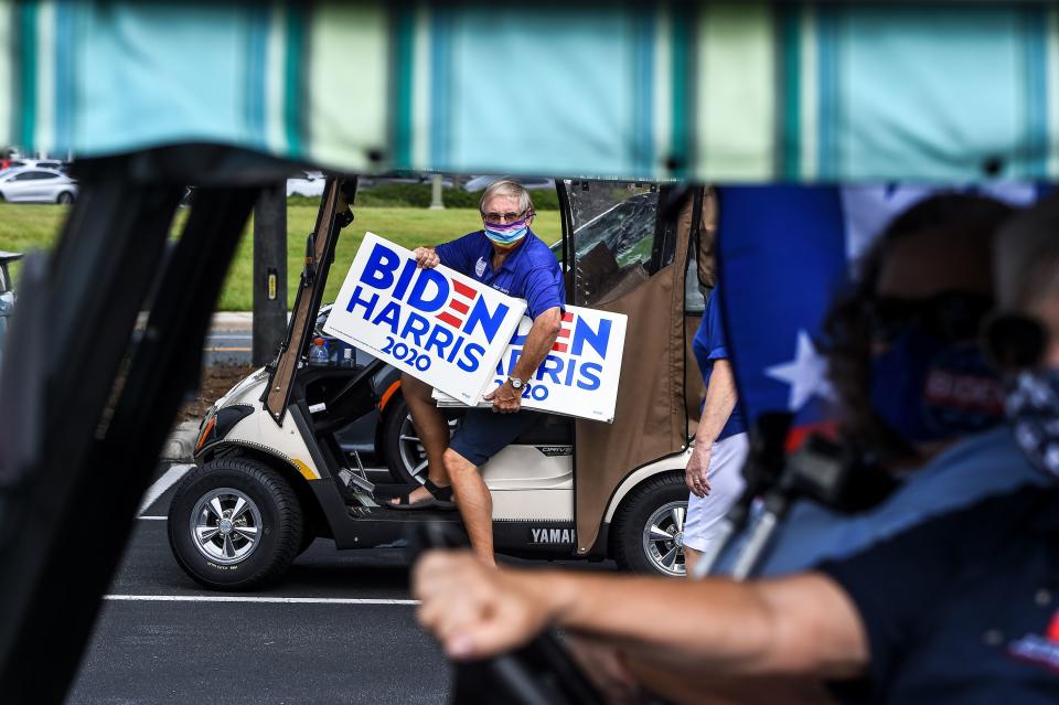 A resident of The Villages, Florida, holds a "Biden Harris 2020" campaign poster on August 21, 2020, as he participates in a golf cart parade to celebrate the nomination of Joe Biden for Democratic presidential candidate and Kamala Harris for vice president. (Chandan Khanna/AFP via Getty Images)